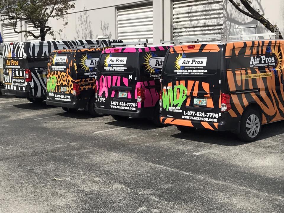 Four Air Pros HVAC service vans are parked side by side in The Villages, each decorated with colorful animal print patterns and bold company branding.