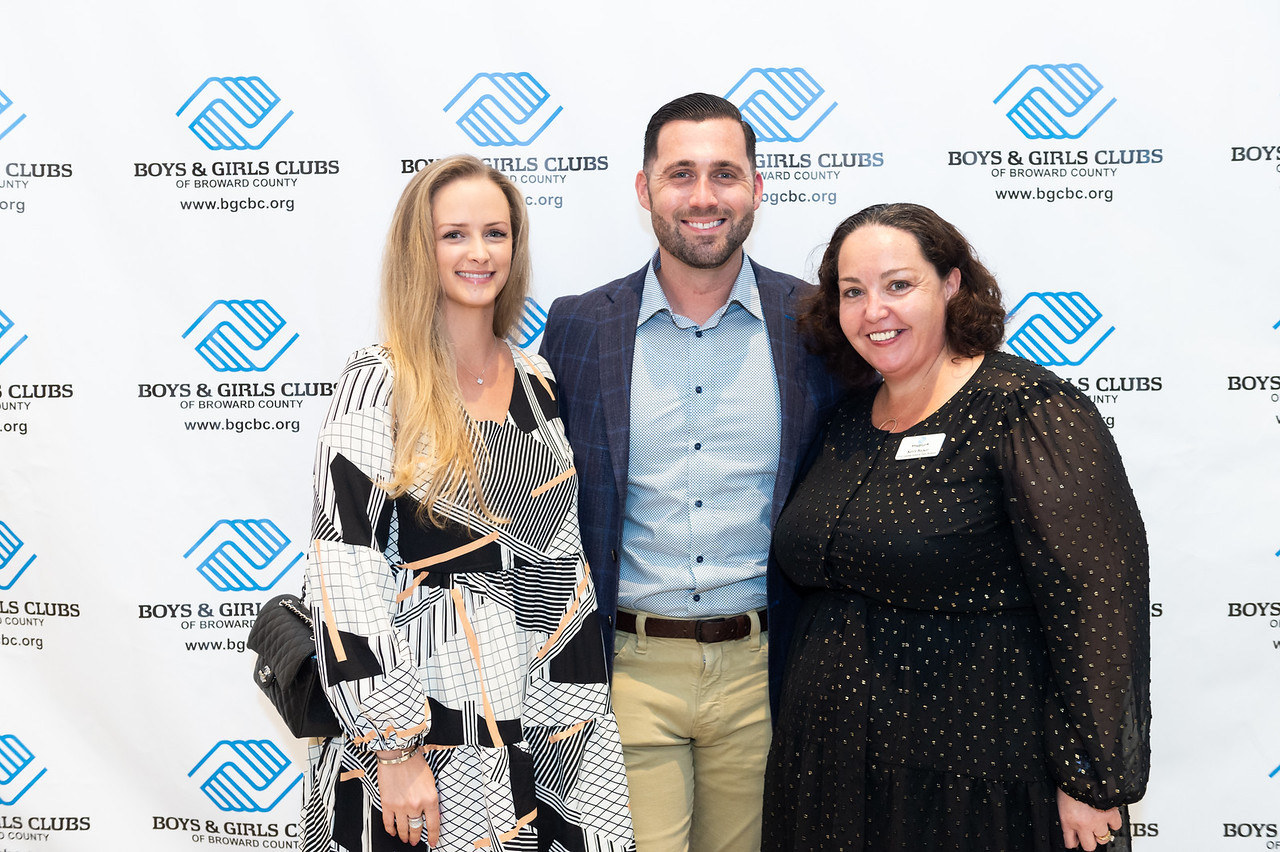 Three people pose in front of a step-and-repeat banner for Boys & Girls Clubs of Broward County at an Air Pros-sponsored Poker Tournament event.