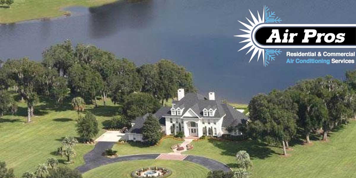 A large house with a circular driveway sits on a landscaped lawn near a lake in Ocala, Florida; the "Air Pros" logo for air conditioning services is in the top right corner.
