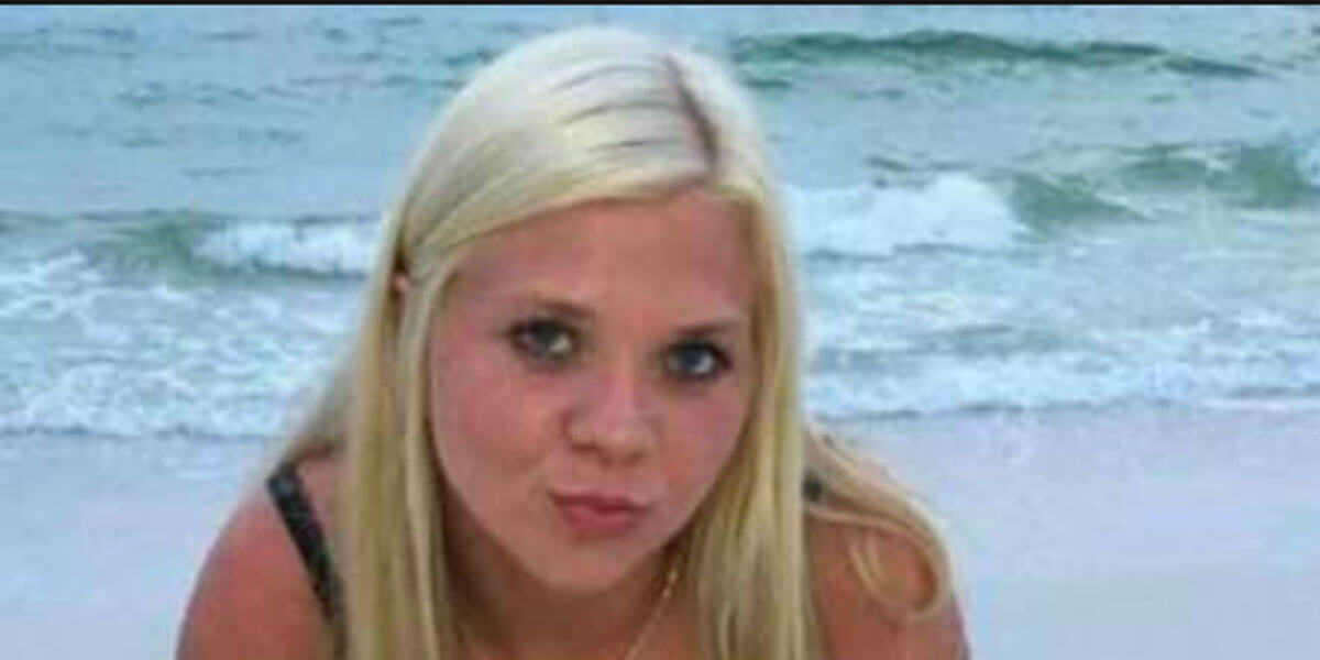 A woman with long blonde hair sits on a sandy beach with ocean waves in the background, reflecting on the importance of home safety.