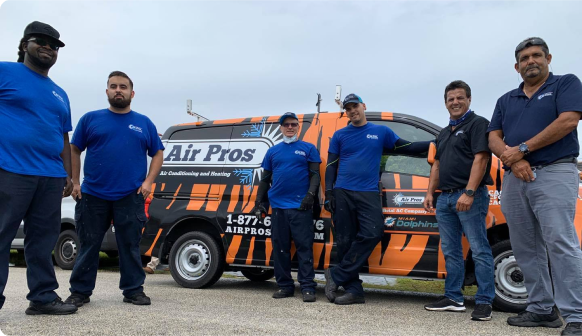 Six men stand in front of an orange and black Air Pros service van, posing for a group photo outdoors—a true success message captured in a moment.