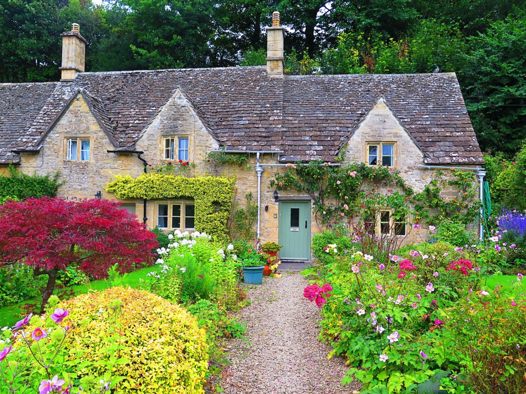Garden and house in UK style. Front of English House. Scenic View of Colorful Flowerbeds and an Attr